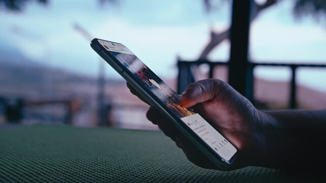 Hands of Woman Holding Phone and Reading Online News Outdoors on Balcony