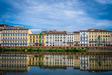 Fototapeta premium Colorful historic buildings line the Arno River in Florence with perfect reflections