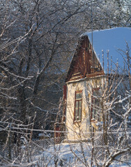 Old Rural House in Winter Garden with Frozen Trees and Snow