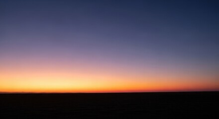 Fototapeta premium Minimalist horizon sunset with orange glow over dark vast landscape