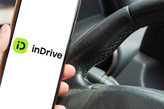 Close-up of a driver using the inDrive app on a cell phone inside a car, a transportation platform with fare negotiation