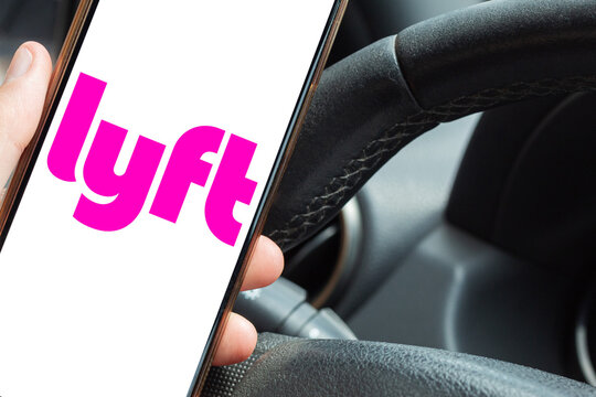 Driver showing the Lyft app on a smartphone from the driver's seat. Ride sharing service concept