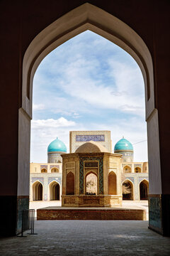 Courtyard view of the Mir-i Arab Madrasa framed by the grand iwan of the Kalyan Mosque in Bukhara, Uzbekistan, showcasing iconic Islamic architecture and blue-tiled domes.