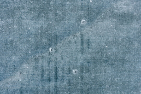 Abstract frozen agricultural field marked with scattered craters and straight lines creating a unique winter texture, aerial top view