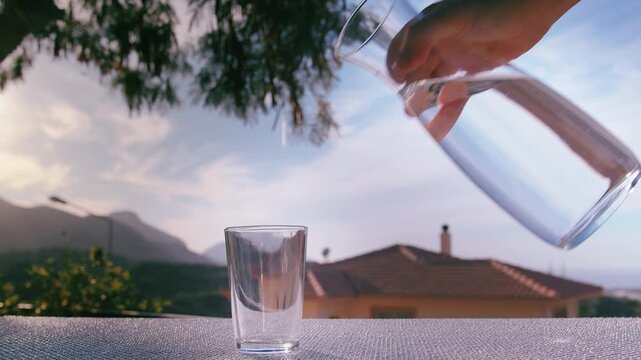 Close-Up of Woman Pouring Pure Water into Glass with Scenic Outdoor Background