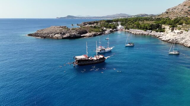 Boats anchored in a sunny bay with swimmers in Rodos Greece