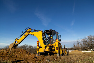 Obraz premium Backhoe loader digging soil at construction site