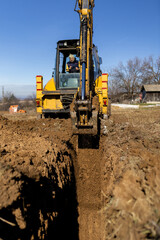 Obraz premium Excavator digging deep trench for foundation