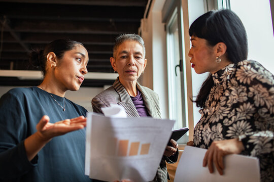 Three businesswomen discussing reports in a modern office