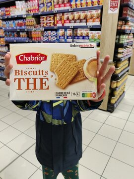 Saujon, France - January 24, 2026: Intermarche. Child holding Chabrior Biscuits THE box in a grocery store aisle with shelves of products visible in the background