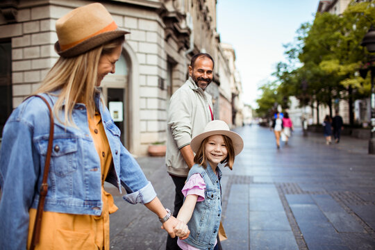 Parents and child walking together on city street