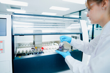 Obraz premium Pathological technician holding biopsy slide rack for quality inspection in clinical lab. Medical scientist preparing tissue sections for microscopic oncological diagnosis.