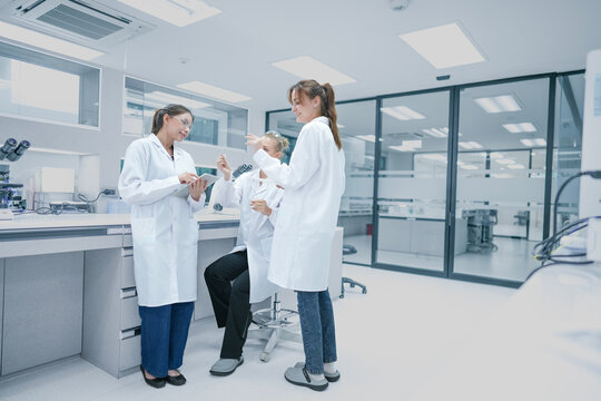 Clinical research associates (CRA) reviewing patient trial compliance data on mobile device. Medical team monitoring regulatory standards in hospital research center.