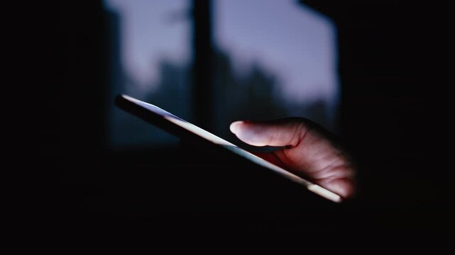 Close-Up of Womans Hand Using Smartphone at Night Near Window