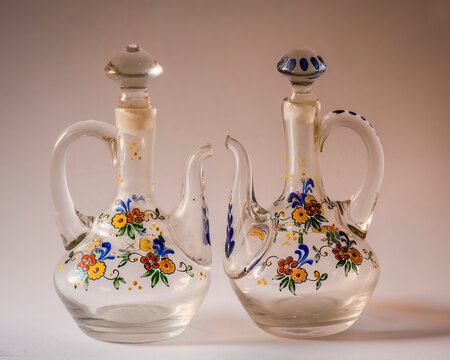 una aceitera y una vinagrera antiguas decoradas con motivos florales