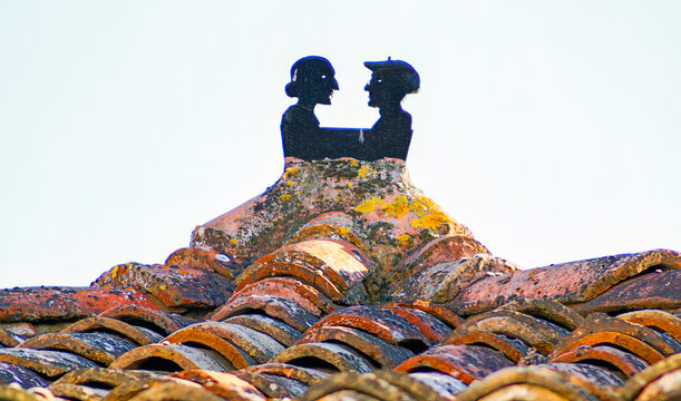 tejado de antiguas tejas con remate de una pareja de ancianos en Burgui, Navarra