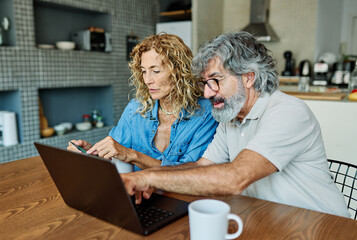 portrait of happy smiling senior elderly couple using a laptop computer and a credit card  for...
