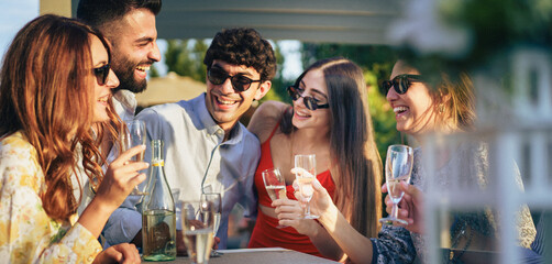 Group of friends celebrating together at rooftop summer party with champagne toast © Lomb