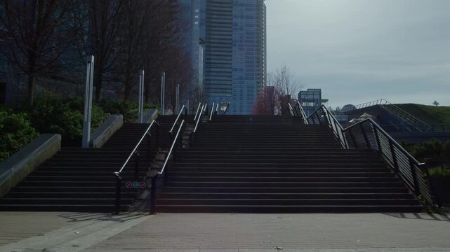 Expansive outdoor staircase leading up to modern city buildings under a cloudy sky