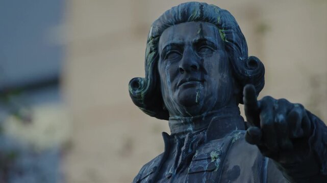 Close-up of a weathered bronze statue of a historical figure pointing forward