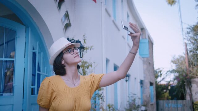 Stylish Young Woman in Hat Taking Selfie on Picturesque European Street with Historic Buildings