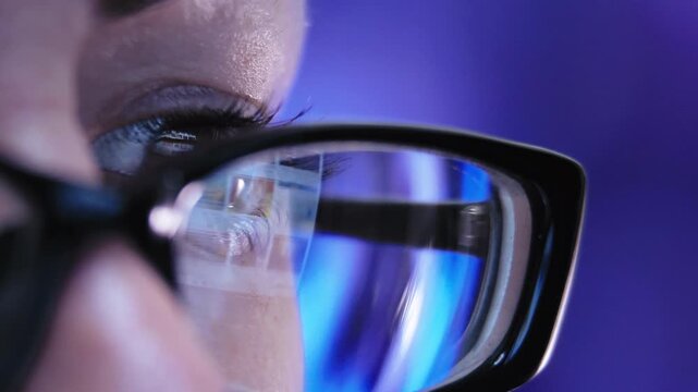 Focused Determination: Close-Up of a Woman's Glasses Reflecting Her Laptop Screen While Working with Intense Efficiency