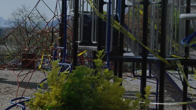 Children's playground equipment cordoned off with yellow caution tape due to closure