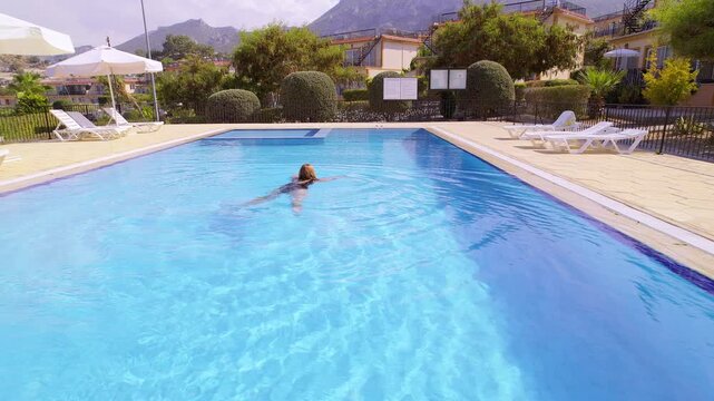 Woman Enjoying Peaceful Leisure in Villa Pool Surrounded by Modern Architecture