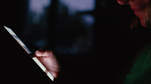 Close-Up of Female Hand Scrolling Smartphone in Low Light by Window
