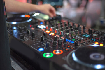 Naklejka premium Close up of DJ Hand Operating Professional Audio Mixer with Bokeh Copy Space