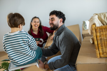 Fototapeta premium Happy family sealing cardboard boxes with adhesive tape in their new apartment.