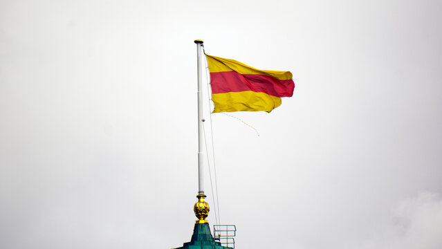 The black-red-gold German national flag flutters in the breeze against a clear sky. Horizontal tricolor stripes symbolize unity, freedom and prosperity in classic proportions. Crisp fabric and vibrant