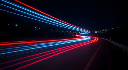 Long exposure photography of red and blue light trails from vehicles on a winding highway at night, symbolizing motion