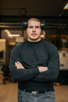 Portrait of male factory worker wearing ear protectors standing with arms crossed