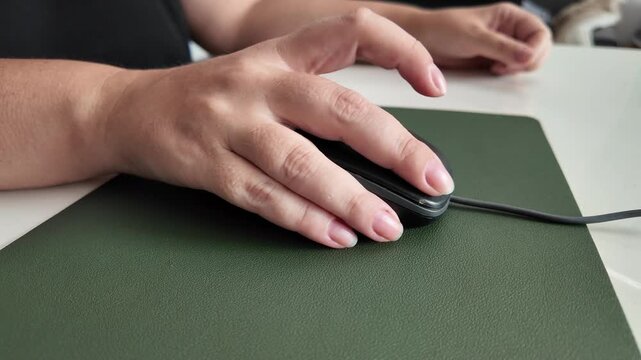 Female using mouse on mouse pad and desk, detail of modern work environment