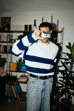 Young man looking through vintage camera at home