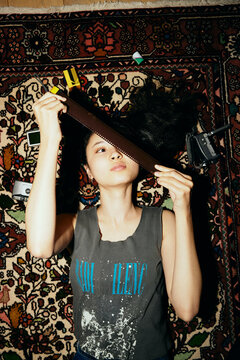 Directly above shot of woman looking at film negative while lying on carpet