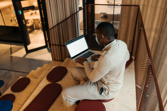 High angle view of young businessman working on laptop while sitting at modern coworking space