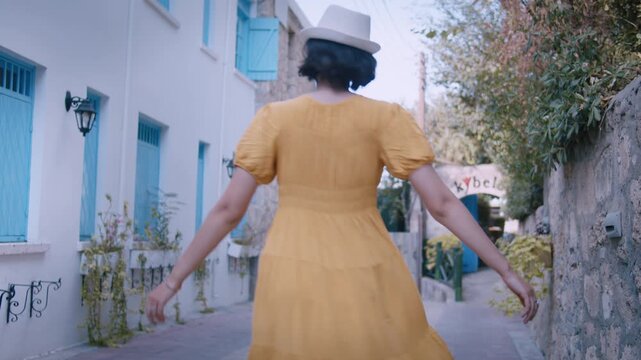 Joyful Woman in Yellow Outfit and Hat Dancing and Turning Around with Happiness on Picturesque European Lane