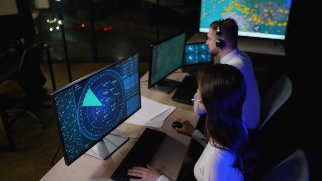 Air traffic controllers monitoring radar in a dark control room