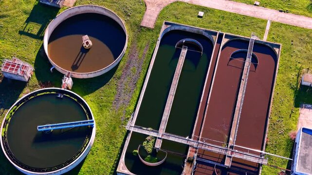 Various shapes of aeration and sedimentation tanks at a wastewater facility. Aerial view of rectangular and circular water treatment basins.
