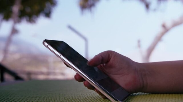 Hands of Young Woman Browsing Internet on Cellphone at Outdoor Veranda with Hills in Background