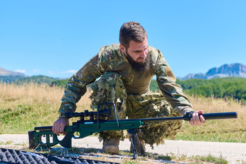 Obraz premium Military Sniper Soldier Preparing Rifle in Open Field Landscape