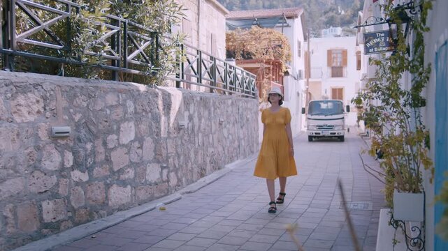 Elegant Woman in Yellow Dress Strolling Through Picturesque European Old Town Street