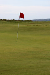 Obraz premium red flag on golf course marking hole