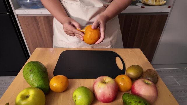 The process of cleaning a mandarin orange. A woman's hands clean a fresh orange