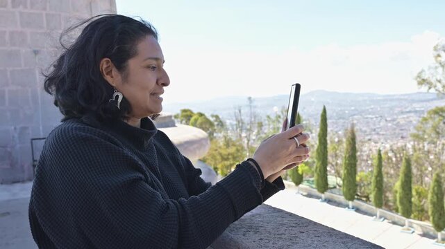Middle-aged Hispanic Woman Capturing Cityscape with Smartphone in Pachuca