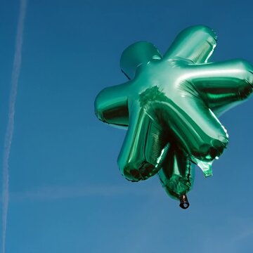 Un globo con forma de estrella verde brillante flotando contra un cielo azul vibrante.