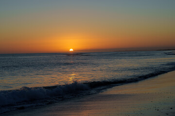 Obraz premium Warm tones of small sphere of sun rising over distant horizon