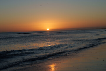 Warm tones of small sphere of sun rising over distant horizon